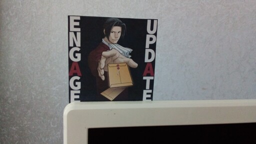 An 8×8 cm picture printed on office paper. It has Miles Edgeworth, protruding his hand towards an updated autopsy report and old one falling below it. Big letters say "ENGAGE UPDATE", with two instances of letter A forming an abbreviation of the Ace Attorney franchise.

Ah, and the picture is standing on the edge of TV set.